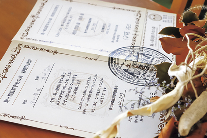 写真：駒ヶ根高原で結婚式を挙げたカップルに交付される「駒ヶ根高原幸せの森　特別住民票」に、ふたりで署名・押印。273組目となる「幸せの森の住民」に